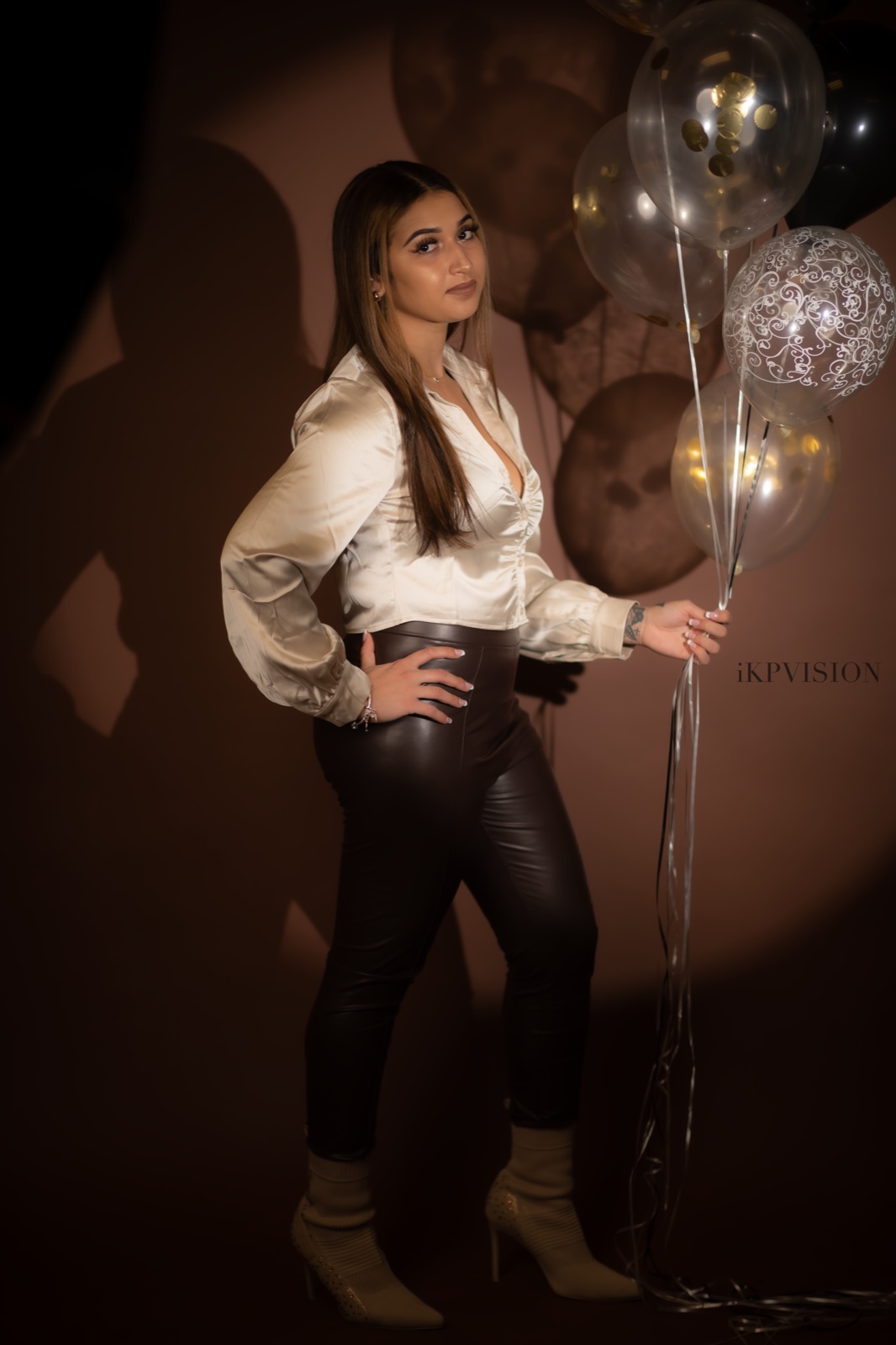 Warm studio portrait holding celebratory balloons.