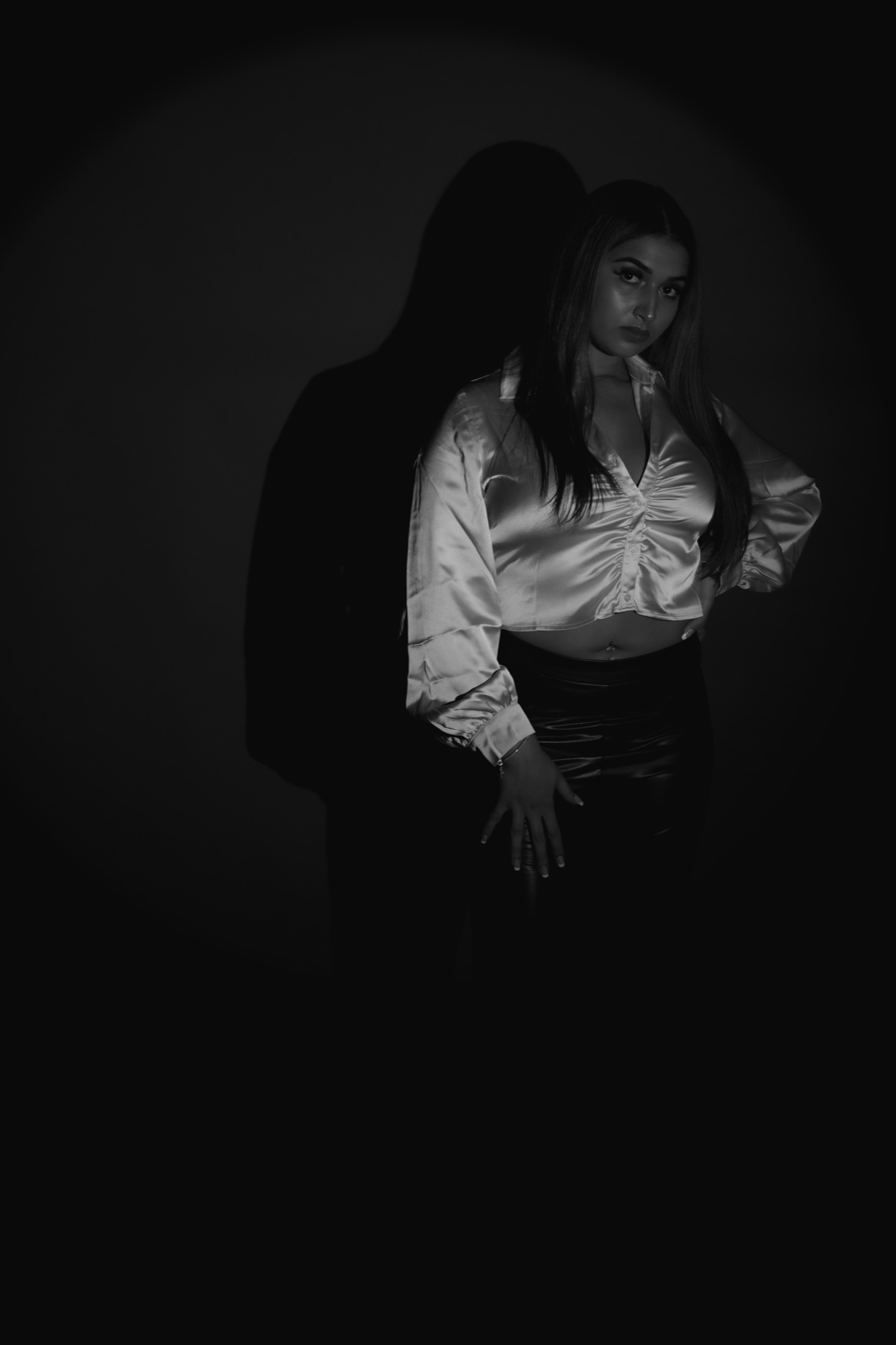 Black-and-white studio portrait with dramatic shadows.